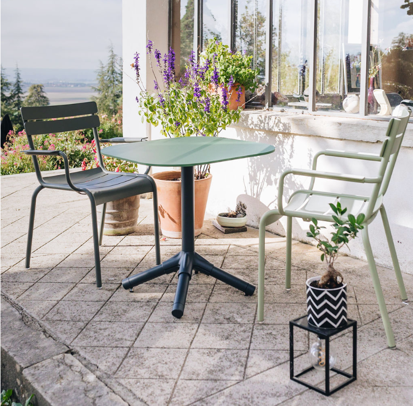 Une table de jardin et deux chaises sur une terrasse fleurie