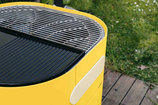 Barbecue marcel charbon jaune sunflower avec côté grille et côté plancha dans jardin avec terrasse en bois - photo rognée