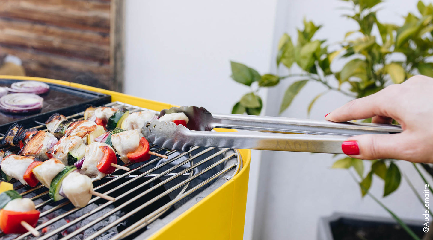 Brochettes en train de cuire sur barbecue design aluvy avec pince inox alimentaire